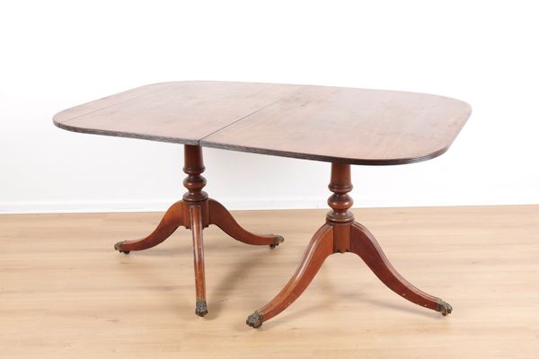 A REGENCY STYLE MAHOGANY TWIN PEDESTAL EXTENDING DINING TABLE