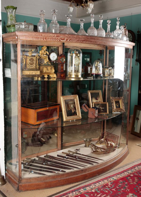 A LIMED OAK BOW FRONT SHOP DISPLAY CABINET