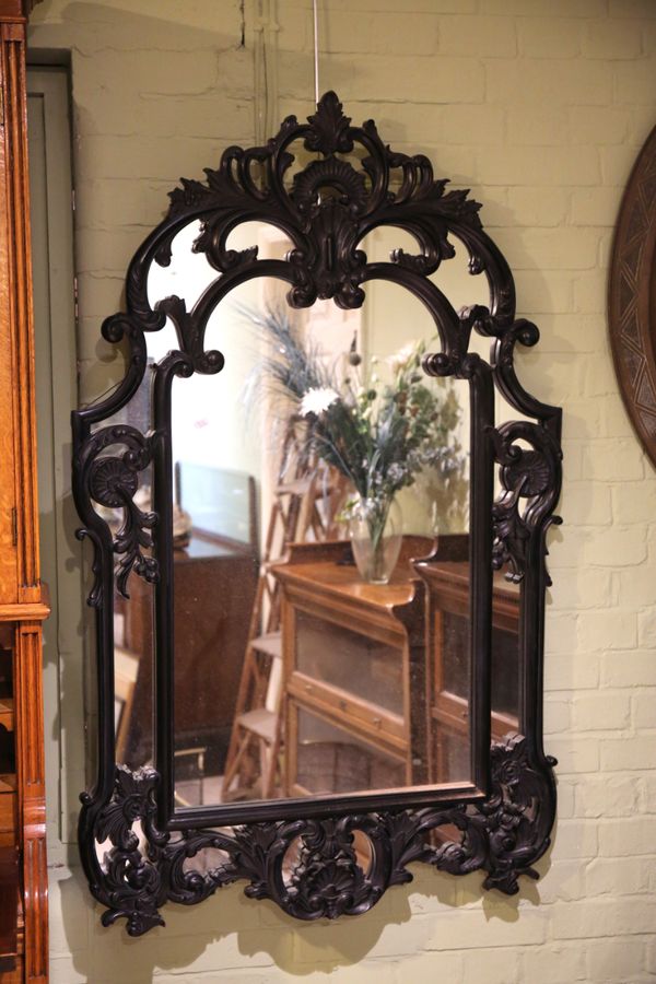 AN EBONISED WOOD WALL MIRROR OF ROCOCO STYLE