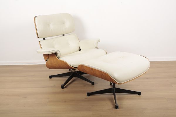 A CREAM LEATHER LOUNGE CHAIR AND OTTOMAN AFTER CHARLES AND RAY EAMES