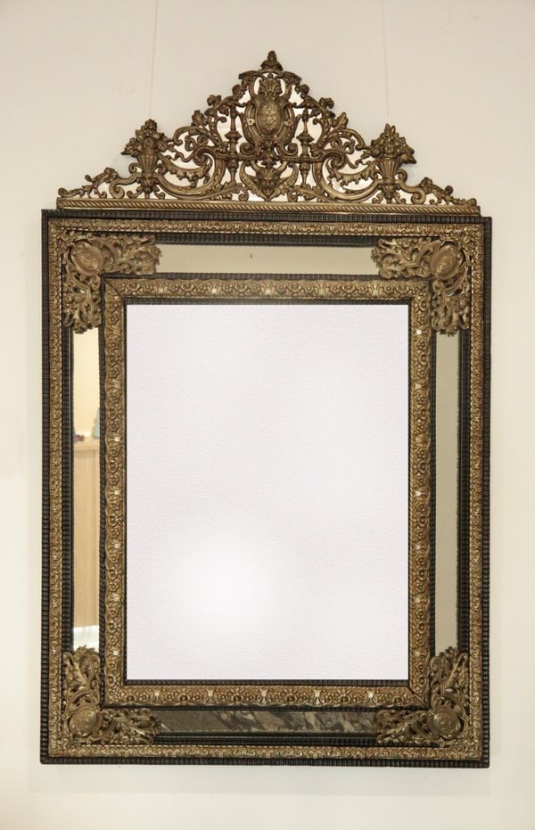 A CHARLES II STYLE REPOUSSE WHITE METAL AND EBONISED WOOD MIRROR