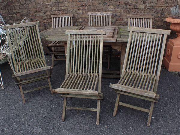 A WEATHERED TEAK EXTENDING GARDEN TABLE AND SIX CHAIRS