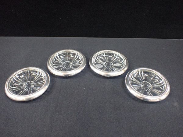 A SET OF SILVER PLATED AND CUT GLASS COASTERS