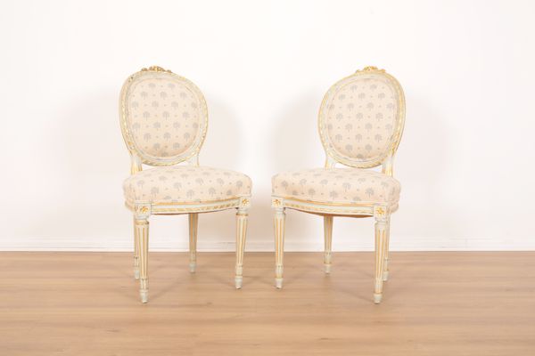 A PAIR OF LOUIS XVI STYLE PAINTED AND PARCEL GILT BEDROOM CHAIRS