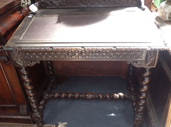 A VICTORIAN CARVED OAK DESK. WITH SLOPING HINGED TOP