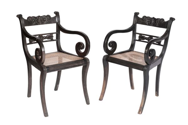 SET OF FOUR CARVED EBONNY AND CANEWORK ELBOW CHAIRS IN ANGLO-INDIAN EARLY 19TH CENTURY STYLE