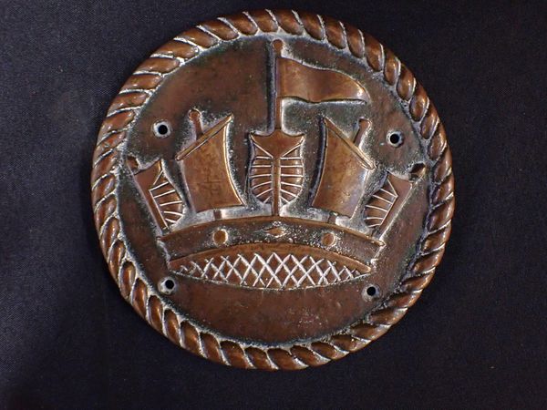 A BRASS PLAQUE, POSSIBLY A NAVAL TAMPION