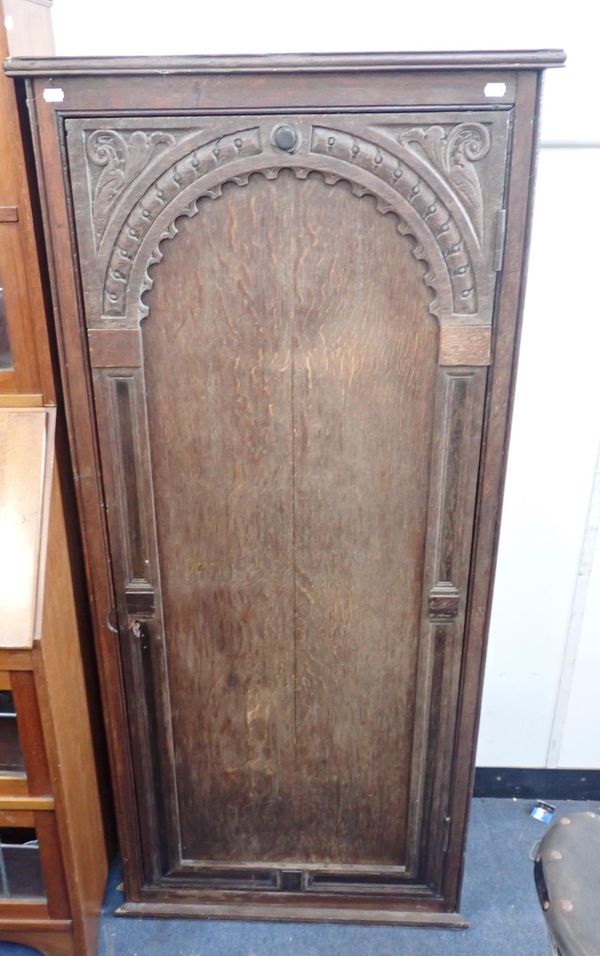 A TALL OAK CUPBOARD WITH A PANELLED DOOR