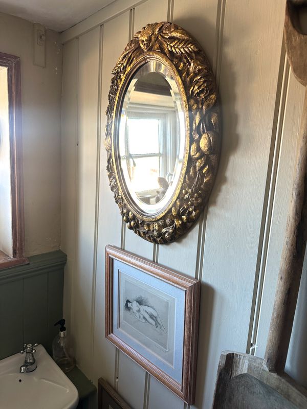 A GILTWOOD OVAL WALL MIRROR