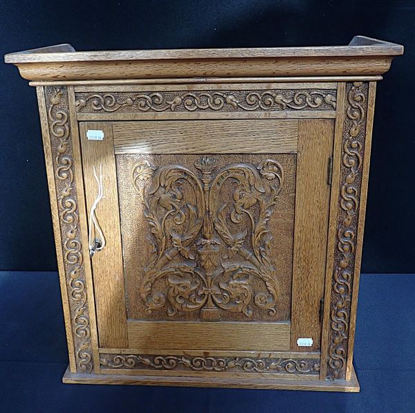 A GOLDEN OAK SMOKERS CABINET, WITH RENAISSANCE STYLE CARVING