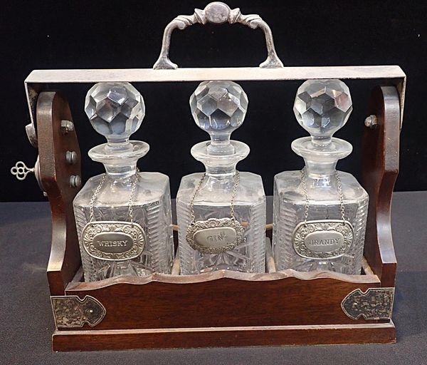 A THREE BOTTLE TANTALUS WITH SILVER-PLATED MOUNTS