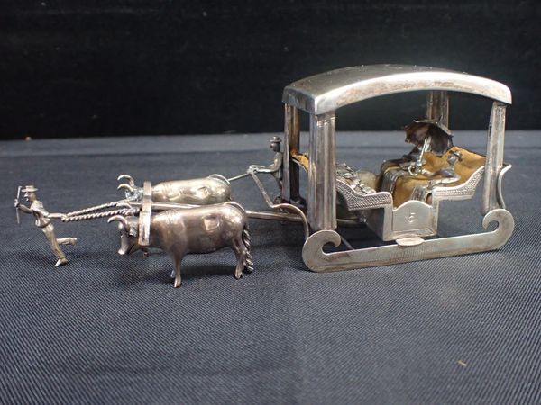 A WHITE METAL MODEL OF AN OXEN DRAWN PASSENGER SLEIGH