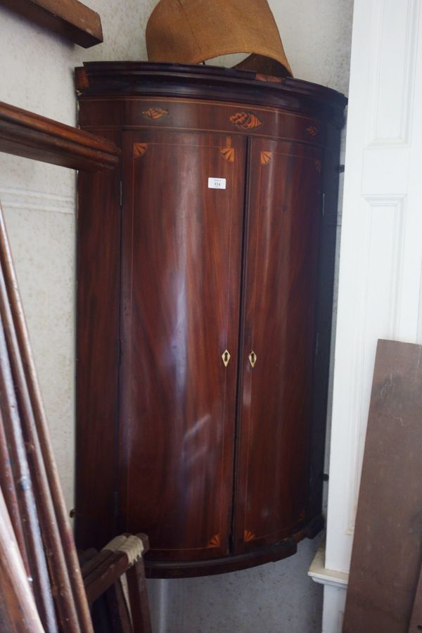 A GEORGE III SHERATON STYLE MAHOGANY BOW FRONT HANGING CORNER CUPBOARD