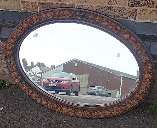 AN EDWARDIAN SIMULATED OAK OVAL WALL MIRROR