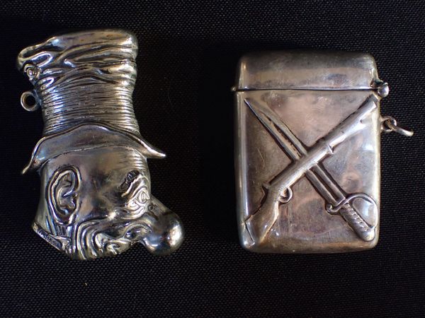 A SILVER VESTA CASE WITH CROSSED RIFLE AND SWORD