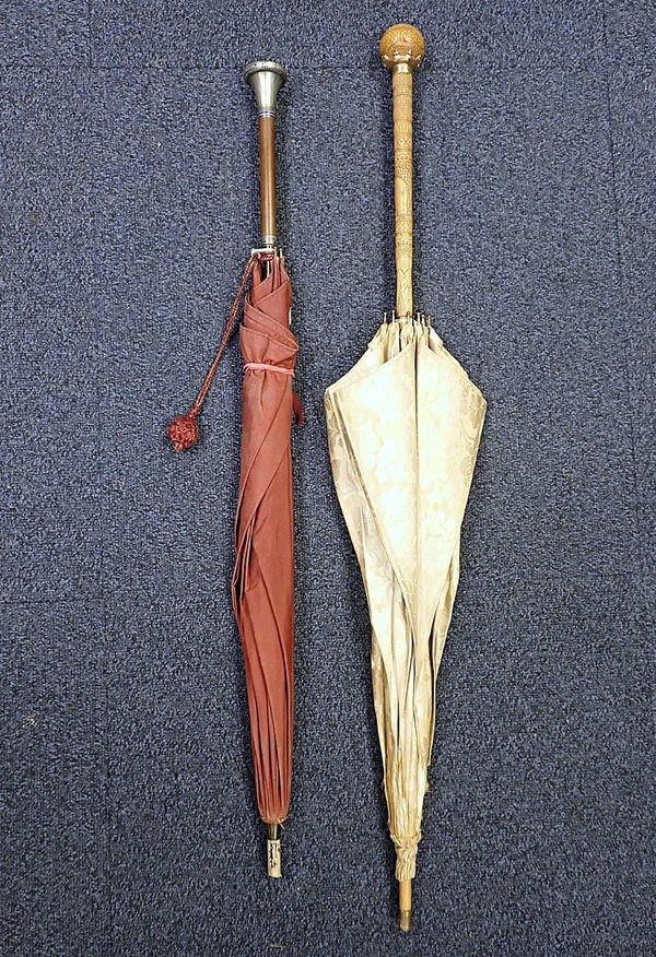 AN UMBRELLA WITH UNMARKED WHITE METAL AND ENAMEL HANDLE