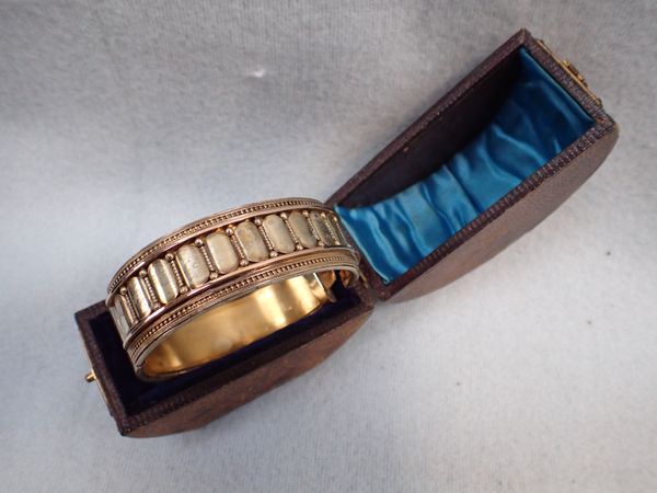A 19TH CENTURY YELLOW AND WHITE METAL BANGLE