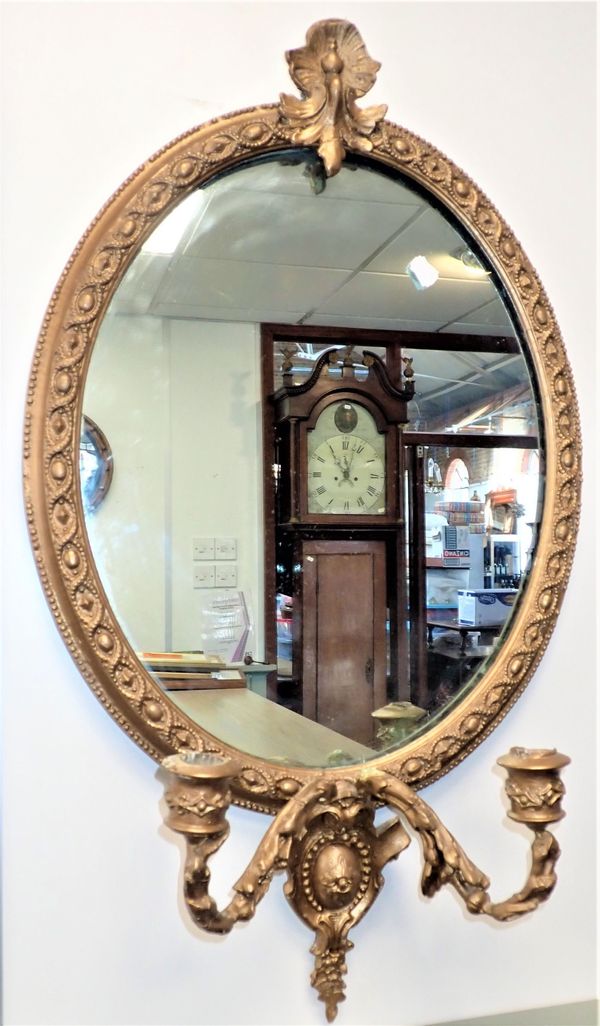 AN OVAL GILT MOULDED FRAMED MIRROR