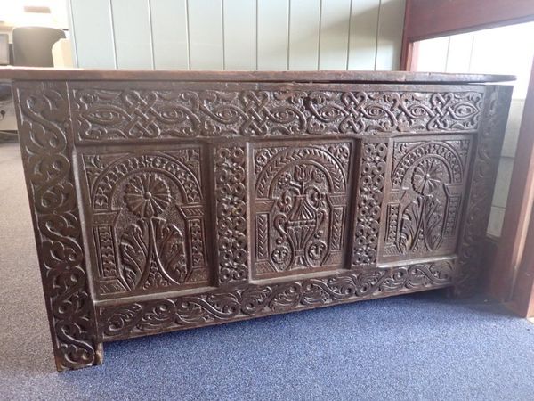 A 17TH CENTURY OAK COFFER WITH PROFUSELY CARVED FRONT
