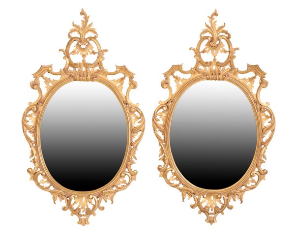 A PAIR OF CARVED AND GILTWOOD FRAMED OVAL WALL MIRRORS, IN ROCOCO TASTE,