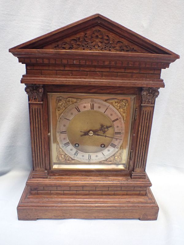 AN EDWARDIAN OAK MANTEL CLOCK OF ARCHITECTURAL FORM