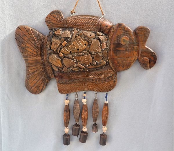 A CARVED WOOD AND POTTERY SHERD EMBELLISHED WIND CHIME