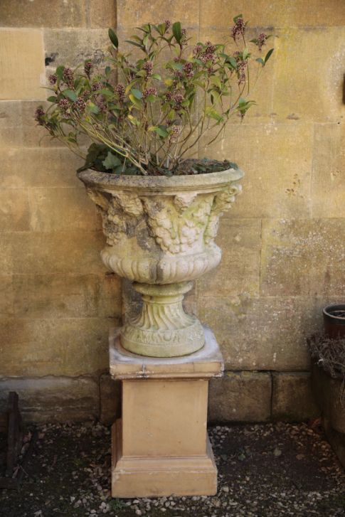 A PAIR OF STONE COMPOSITION GARDEN URNS BY AUSTIN & SEELEY, ON ASSOCIATED PLINTHS,