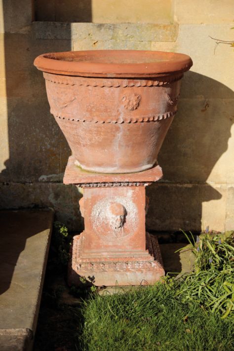 TWO SIMILAR TERRACOTTA GARDEN URNS ON PLINTHS,