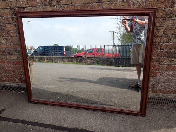 A LARGE BEVEL EDGED STAINED PINE MIRROR