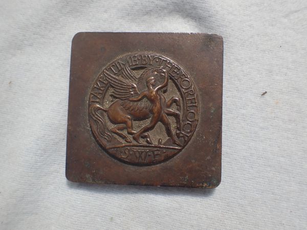 A CAST BROZE PLAQUE: 'TAKE TIME BY THE FORELOCK' -'S.W.F.'