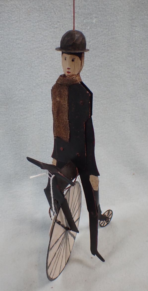 A 'FOLK ART' JOINTED TIN FIGURE ON A 'PENNY FARTHING' BICYCLE