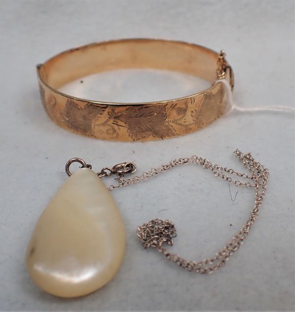 A ROLLED GOLD HINGED BANGLE AND A MOTHER OF PEARL PENDANT