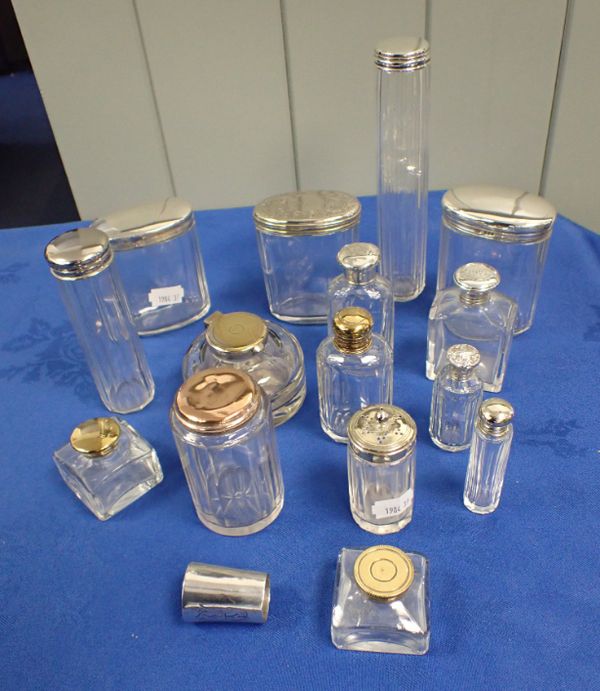 A COLLECTION OF WHITE METAL AND PLATED TOPPED GLASS BOTTLES