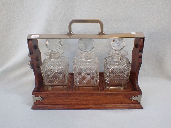 A OAK THREE DECANTER TANTALUS, WITH NICKEL-PLATED MOUNTS