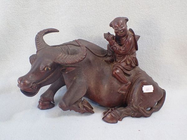 AN ASIAN WOODEN STATUE OF A BOY RIDING A BULL