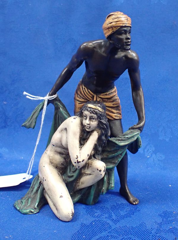 A COLD PAINTED BRONZE; AN EASTERN FIGURE COVERING A NUDE WOMAN