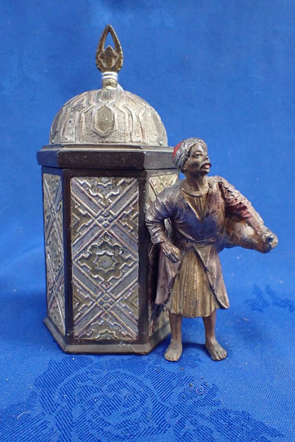 A COLD PAINTED SPELTER EASTERN TRADER NEXT TO A HEXAGONAL BUILDING