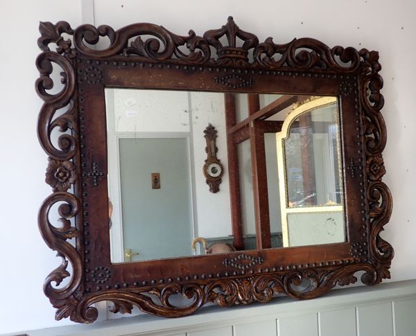 A 1920s CAROLEAN STYLE CARVED OAK AND LEATHER FRAMED WALL MIRROR