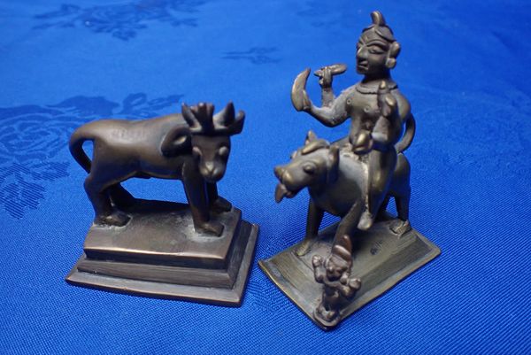 A SMALL BRASS INDIAN FIGURE OF A DEITY RIDING A MYTHICAL BEAST