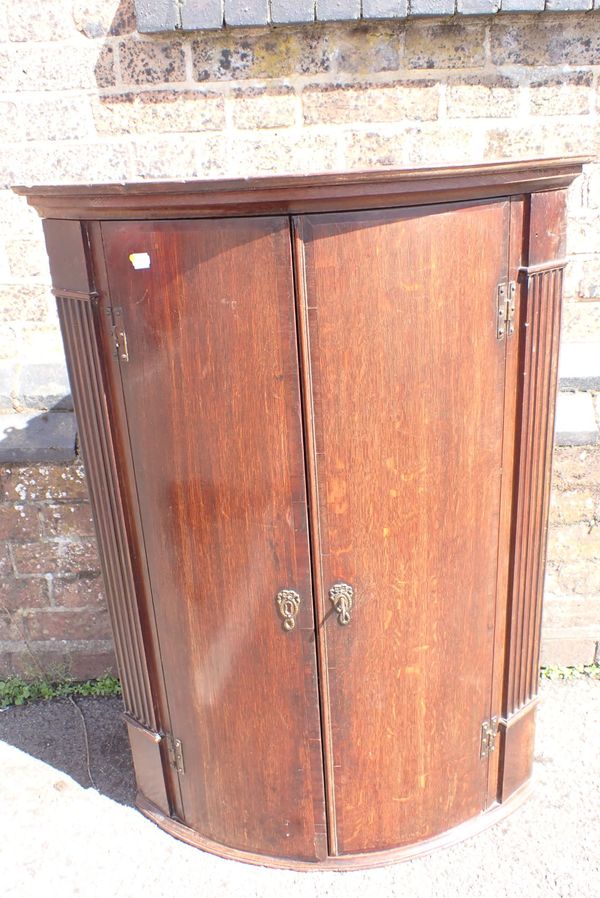 A GEORGE III OAK BOWFRONT HANGING CORNER CUPBOARD