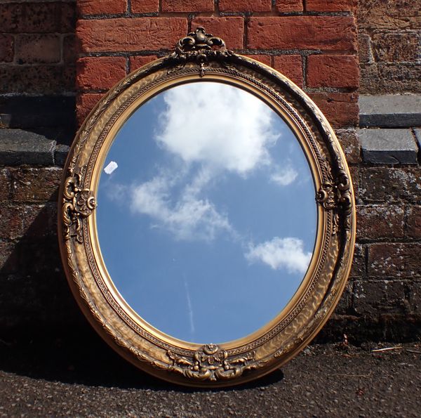 A GILT FRAMED OVAL WALL MIRROR