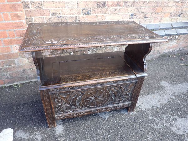 AN OAK MONK'S BENCH WITH CARVED FRONT PANEL