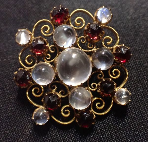 AN EDWARDIAN GOLD COLOURED METAL, MOONSTONE AND GARNET BROOCH