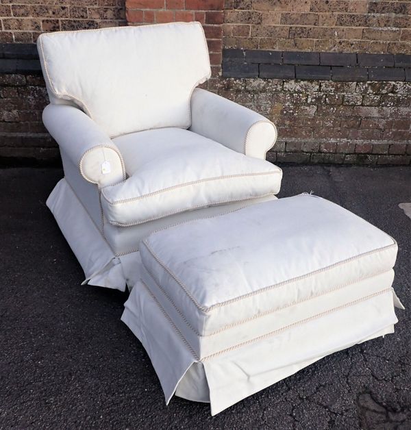 A CREAM UPHOLSTERED ARMCHAIR AND FOOTSTOOL