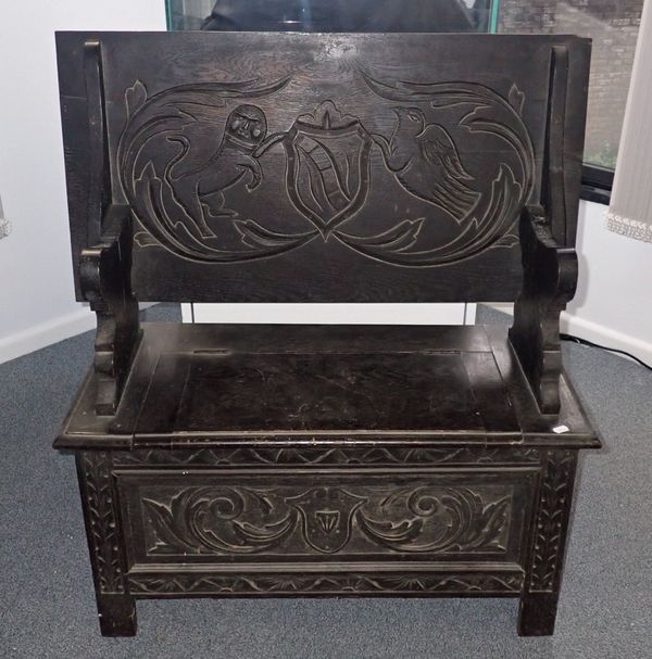 A LATE VICTORIAN CARVED AND EBONISED OAK MONKS BENCH