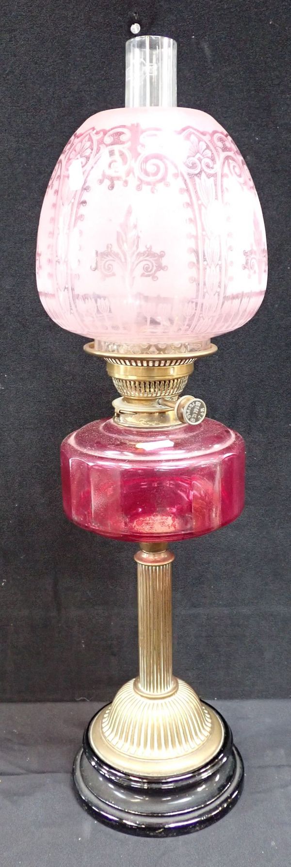 A 19TH CENTURY BRASS TABLE OIL LAMP WITH PNK GLASS RESERVOIR AND SHADE