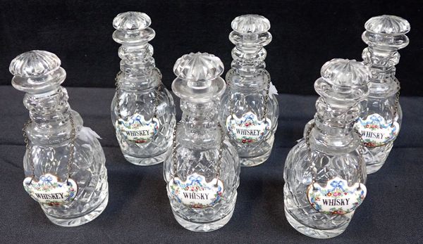 A SET OF SIX SMALL CUT GLASS DECANTERS, WITH PORCELAIN LABELS