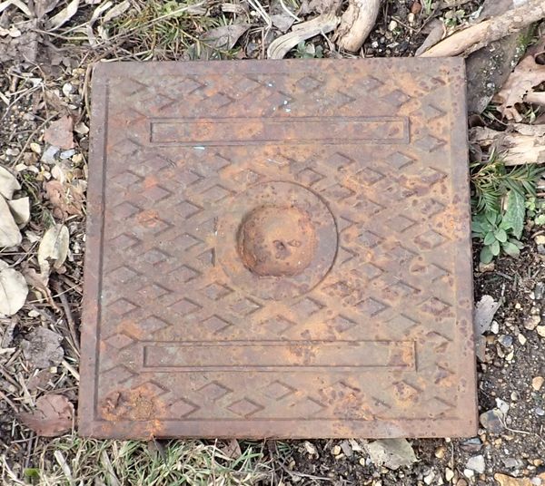 AN OLD CAST IRON SQUARE DRAIN COVER