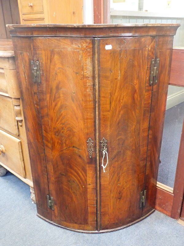 A GEORGE III FIGURED MAHOGANY BOWFRONT CORNER CUPBOARD