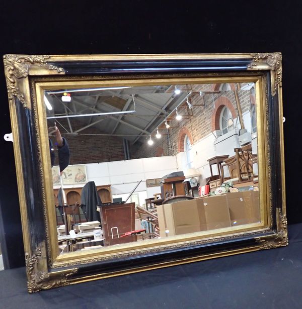 A WALL MIRROR, EBONISED AND GILT